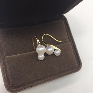 Macro shot of gold hook earrings featuring white freshwater pearls in a velvet jewelry box