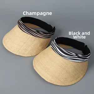 Detail view of woven raffia sun visors with champagne and black zebra stripe ribbon bands