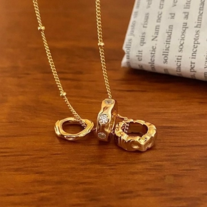 Detail of gold-plated 925 silver necklace with triple-ring pendant on a wooden background