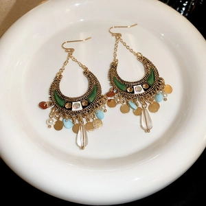 Detail of bohemian crescent earrings with colorful beads and sequins on white porcelain