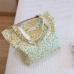 Detail of floral cotton handbag featuring a zipper and cream canvas handles on white fabric