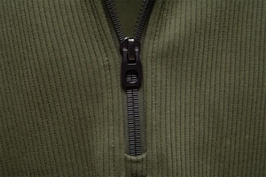 Macro shot of durable metal zipper and ribbed texture on army green men's sweatshirt
