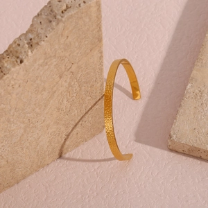 Macro view of golden hammered texture cuff bracelet placed between natural stones