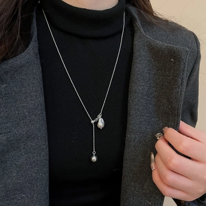Detail of silver pea pendant Y-necklace worn over a black sweater for an elegant look