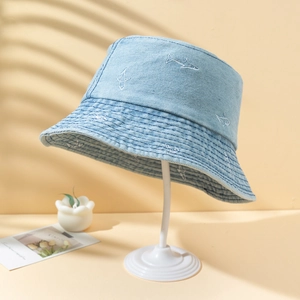 Light blue denim bucket hat with shark embroidery on a white minimalist display stand