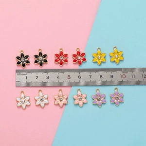 Detailed view of 15mm colorful enamel flower pendants with ruler for size reference