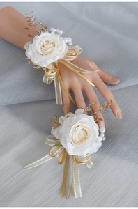 Dettaglio di fiori da polso con rose bianche artificiali e nastri dorati set da 2
