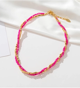 Detail of double-layer necklace with rose red beads and golden geometric blocks on white silk