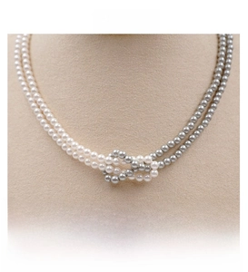 Detail view of double-layered pearl necklace with white and grey beads and a knotted design