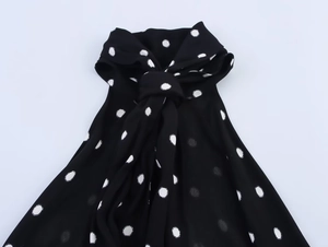 Dettaglio di un abito a pois neri con scollo a fiocco e trama in chiffon leggero