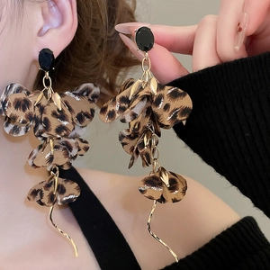 Detailed view of leopard print fabric flower earrings with long gold tassel and black stone