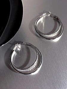 Detail of silver double-layered hoop earrings with smooth and textured metal finishes