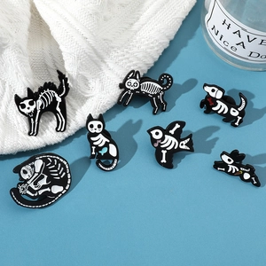 Detail of dark skeleton cat and animal enamel pins on a white knitted sweater