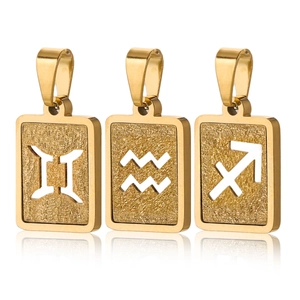 Detailed macro of 18K gold-plated zodiac pendants with frosted matte finish on white surface