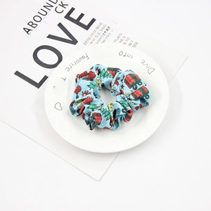 Close-up of light blue Christmas hair scrunchie with festive tree and gift box patterns