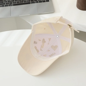 Détail intérieur d'une casquette beige avec broderie LOVE et motif de cœur doré