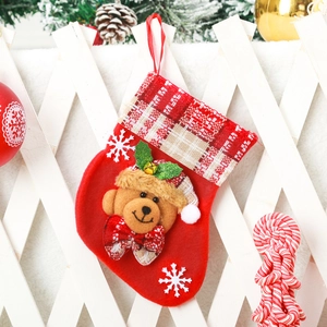 Detail of red fabric Christmas stocking with 3D teddy bear and red white plaid cuff