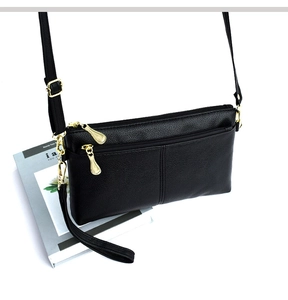Detail of black lychee grain leather crossbody bag with three golden zippers and textures