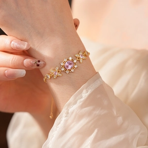 Close-up of vintage gold bracelet with pink oval zircon and flower detail on wrist