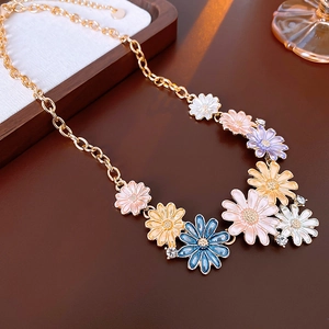 Detailed close-up of colorful enamel daisy charms on a gold-tone necklace chain