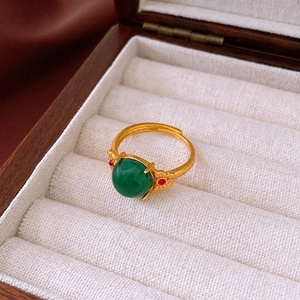 Détail de la bague ajustable dorée avec pierre ovale verte et finition texturée rétro