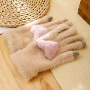 Detail of beige faux mink plush gloves with pink heart decor on a wooden background