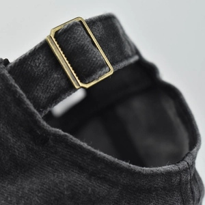 Macro detail of adjustable brass buckle and vintage corduroy texture on baseball cap