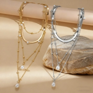 Layered gold and silver necklaces with elegant white pearls and teardrop pendants