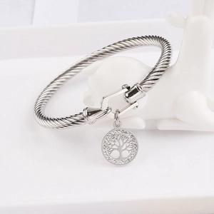 Silver cable cuff bracelet with tree of life charm and horseshoe buckle on white prop
