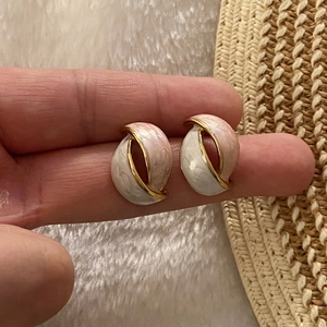 Golden twist petal earrings with beige and pink marble enamel finish held in hand