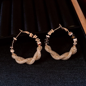 Détail de boucles d'oreilles dorées géométriques avec texture de maille tressée