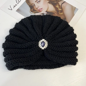 Detailed texture of black knit turban hat with vintage silver and purple jewel ornament
