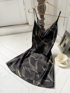 Détail d'une nuisette en soie noire avec imprimé feuilles dorées et col en dentelle