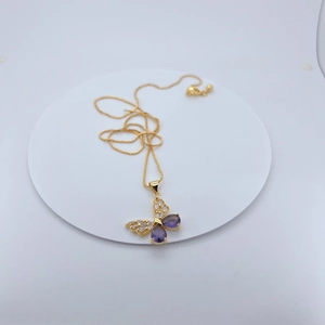 Macro shot of gold-plated butterfly pendant with purple stones on a white base