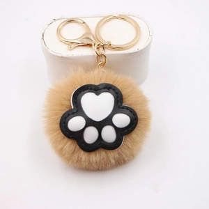 Detail of a fluffy beige cat paw keychain with soft faux fur and gold metal clasp