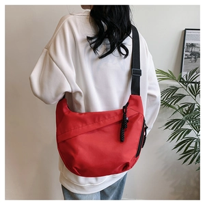 Red crossbody tote bag with adjustable black strap shown on model's shoulder