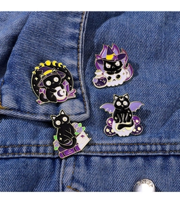 Detail of four black magic cat enamel pins on blue denim jacket collar and pocket
