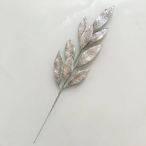 Macro shot of silver glitter coated artificial branch with detailed leaf textures for decor
