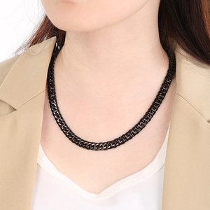 Detailed view of a black Cuban link chain on a model wearing a beige suit jacket
