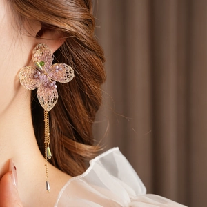 Close-up of vintage gold woven flower earrings with purple beads and green gemstone