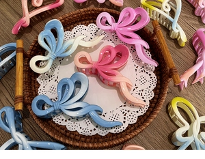 Macro view of gradient bow hair claws on a wooden tray with lace detailing