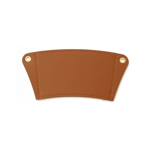 Flat lay detail of brown leather coffee cup sleeve with metal eyelets and stitching