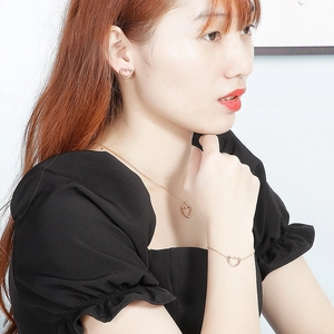 Three-piece rose gold stainless steel jewelry set with hollow heart pendants worn by model