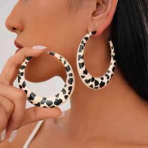 Detailed view of large black and white spotted hoop earrings with cow print texture