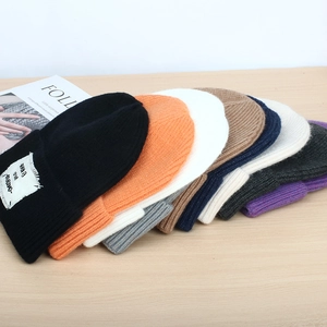 Detailed fan-shaped display of multi-color knitted beanies on a light wooden surface