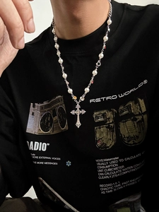 Detail of men's necklace with imitation pearls, colorful gems, and silver cross pendant