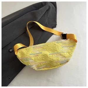 Detailed view of yellow quilted fabric texture and black buckle on a modern chest bag