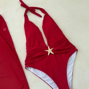 Detail view of red halter neck swimsuit with gold starfish buckle and waist pleats
