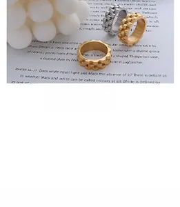 Detail of wide stackable rings with square gear texture in gold and silver finish