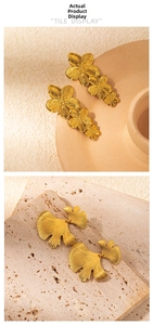 Macro detail of gold-plated ginkgo leaf and layered floral earrings with brushed texture